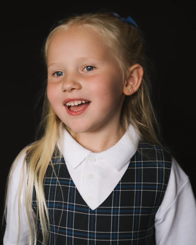 A primary school student smiling in uniform