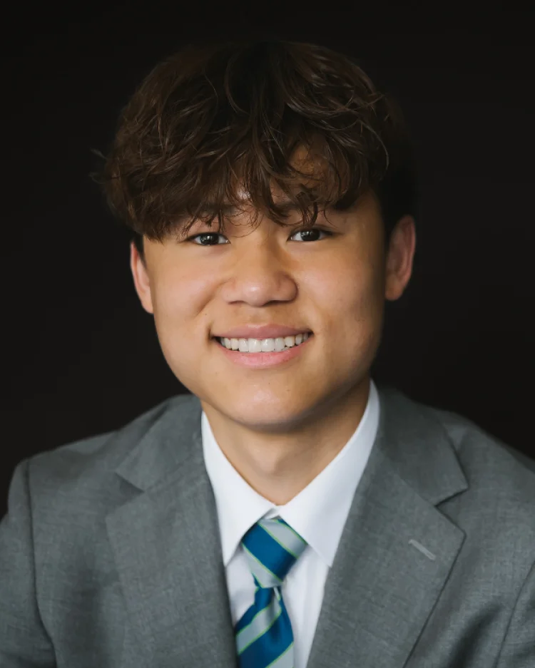 A sixth form student in a uniform smiling